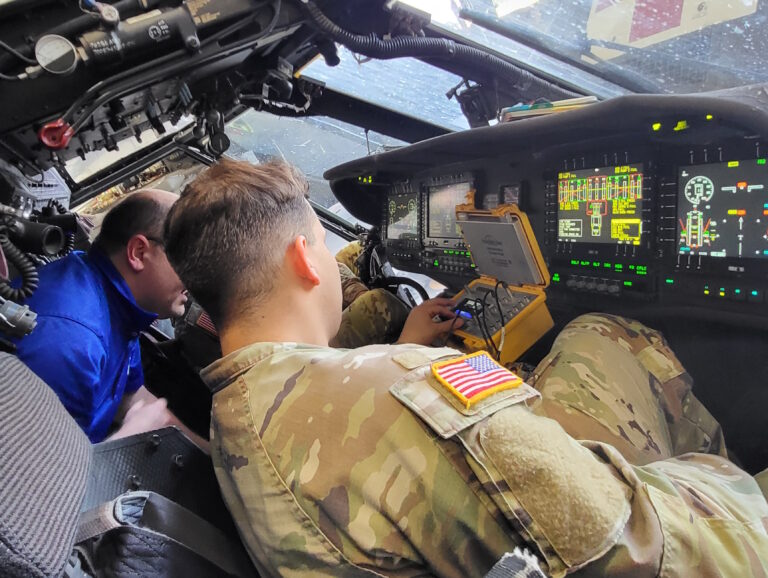 Maintainers using aircraft-connected diagnostic equipment inside a cockpit.